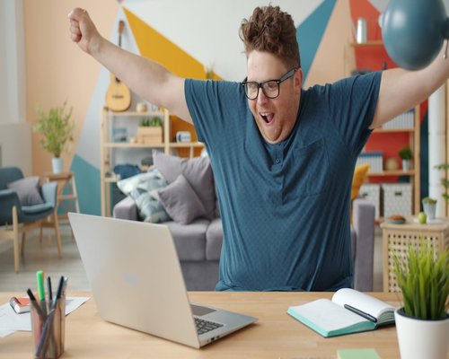 A person stretching their arms slightly while sitting at a desk at home